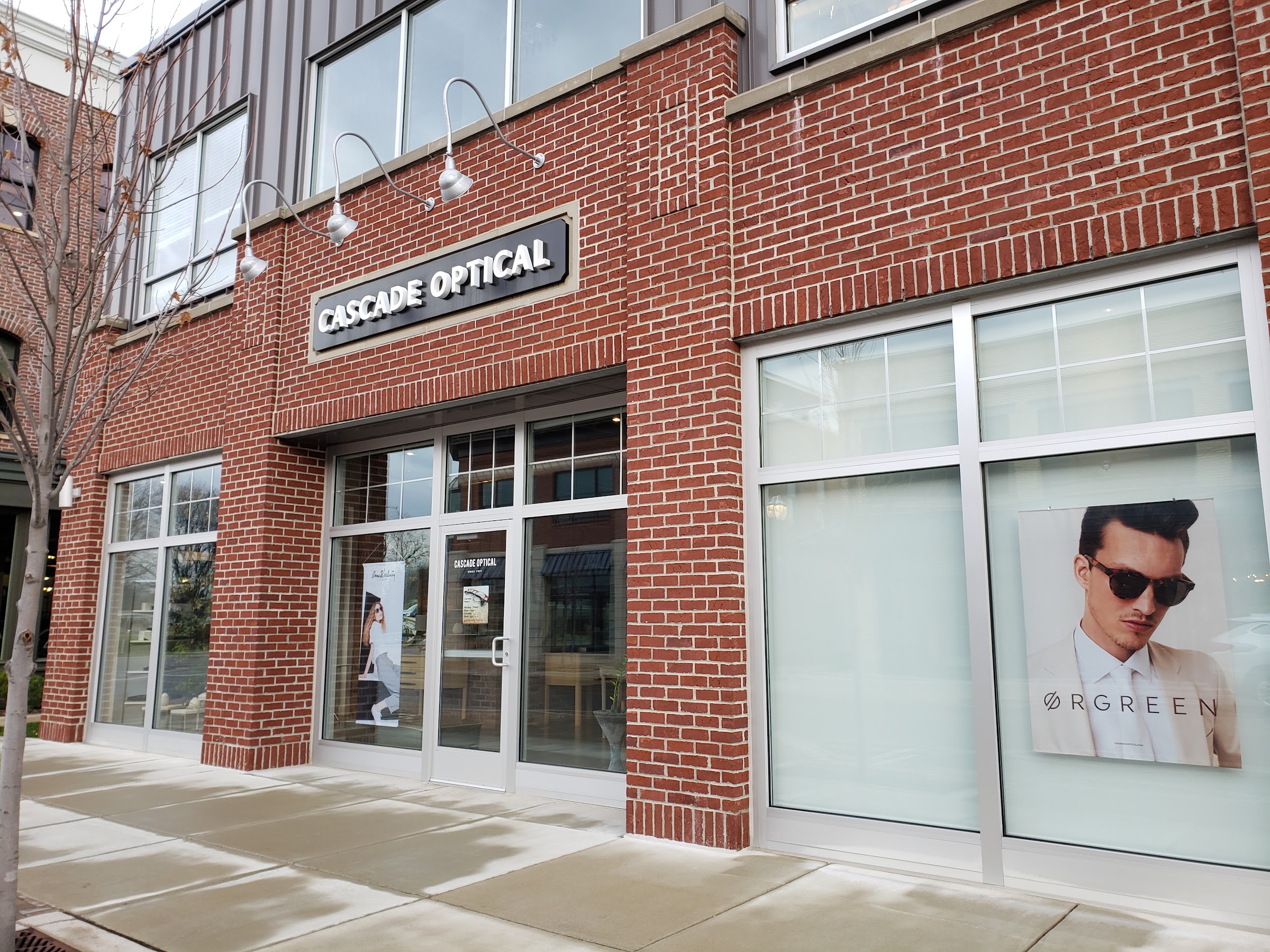 Cascade Optical storefront in Ada Village — red brick facade with the illuminated CASCADE OPTICAL sign and an Ørgreen window display.